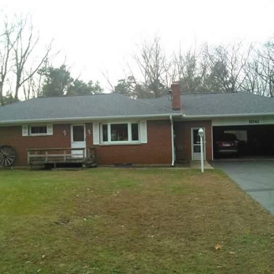 A brick house with a car parked in the driveway.