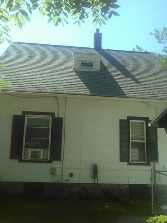 A white house with black shutters and a chimney on the roof