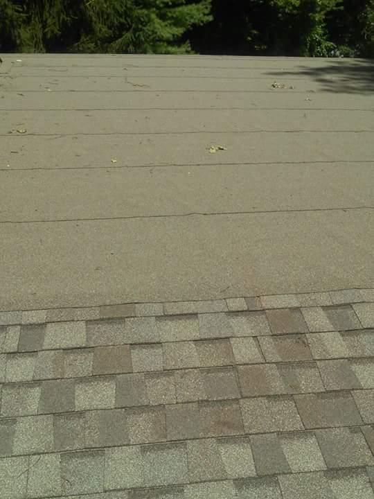 A close up of a roof with shingles and trees in the background.