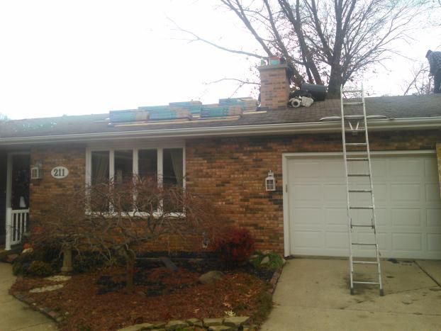 A ladder is sitting in front of a brick house.