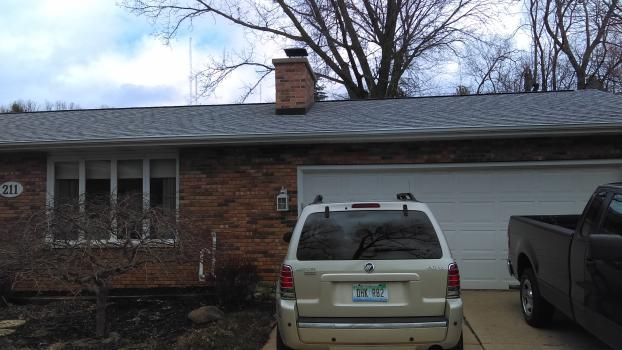 A silver suv is parked in front of a brick house
