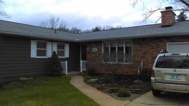 A white van is parked in front of a brick house.