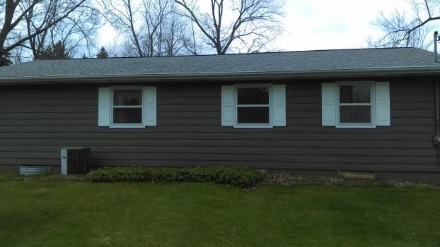 A brown house with white shutters on the windows