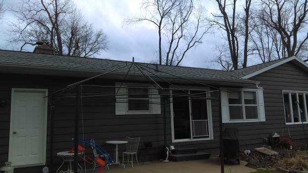 The back of a house with a patio and trees in the background.