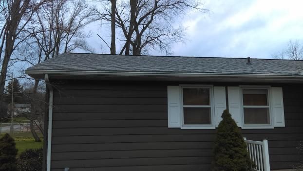 A small house with a roof and white shutters