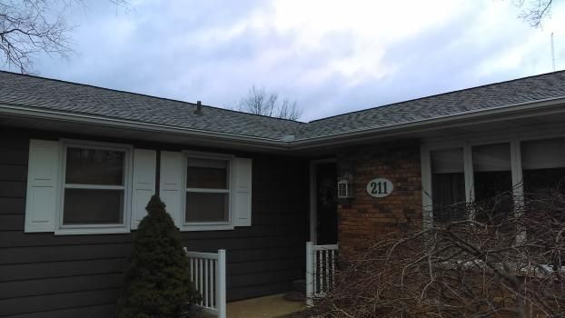 A black house with white shutters and a gray roof.