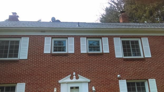 A red brick house with white shutters on the windows