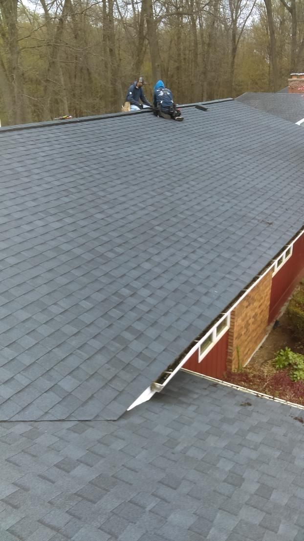 A man is sitting on the roof of a house.