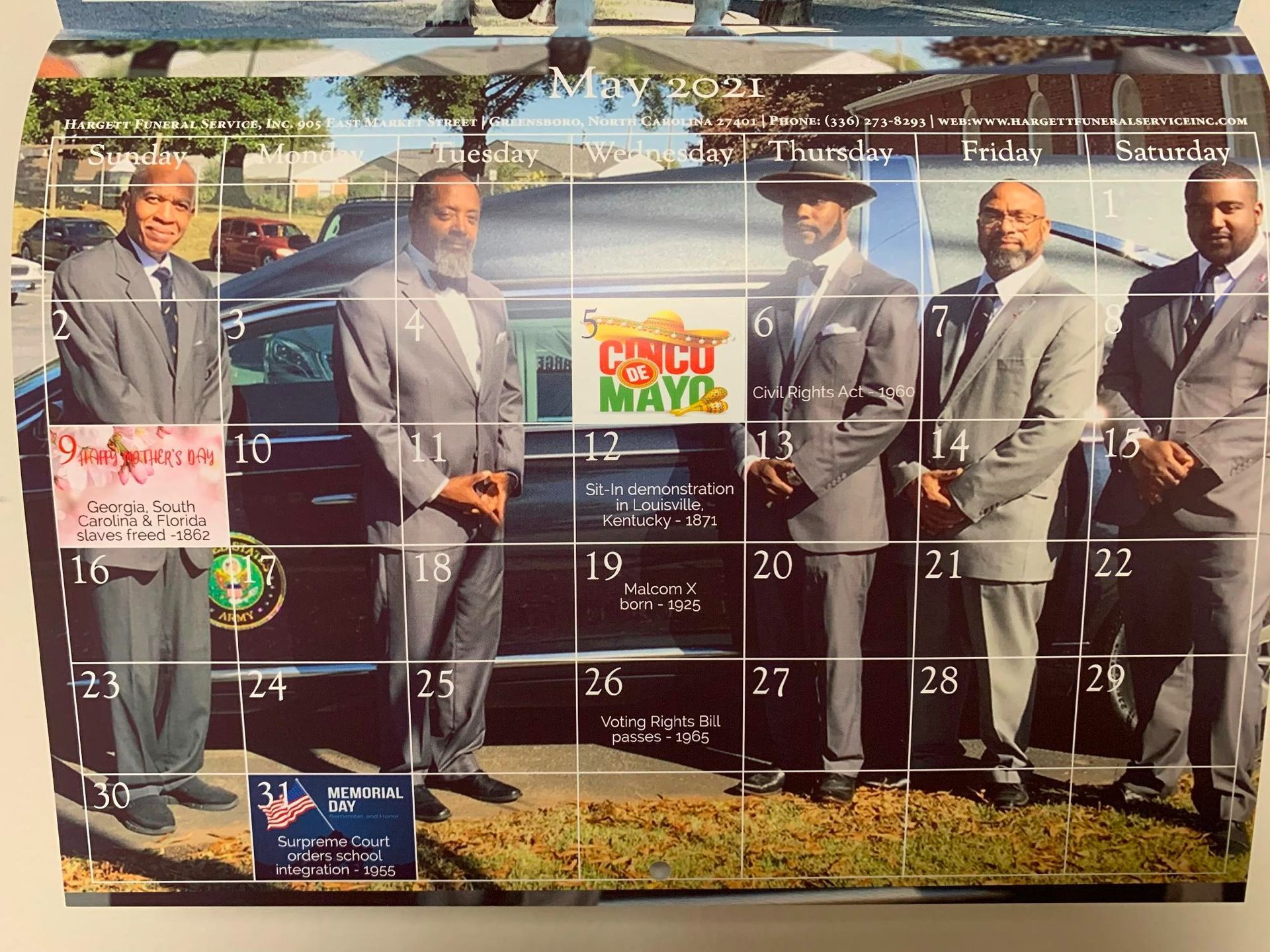 Calendar page featuring five men in gray suits standing near a hearse; Cinco de Mayo is featured.