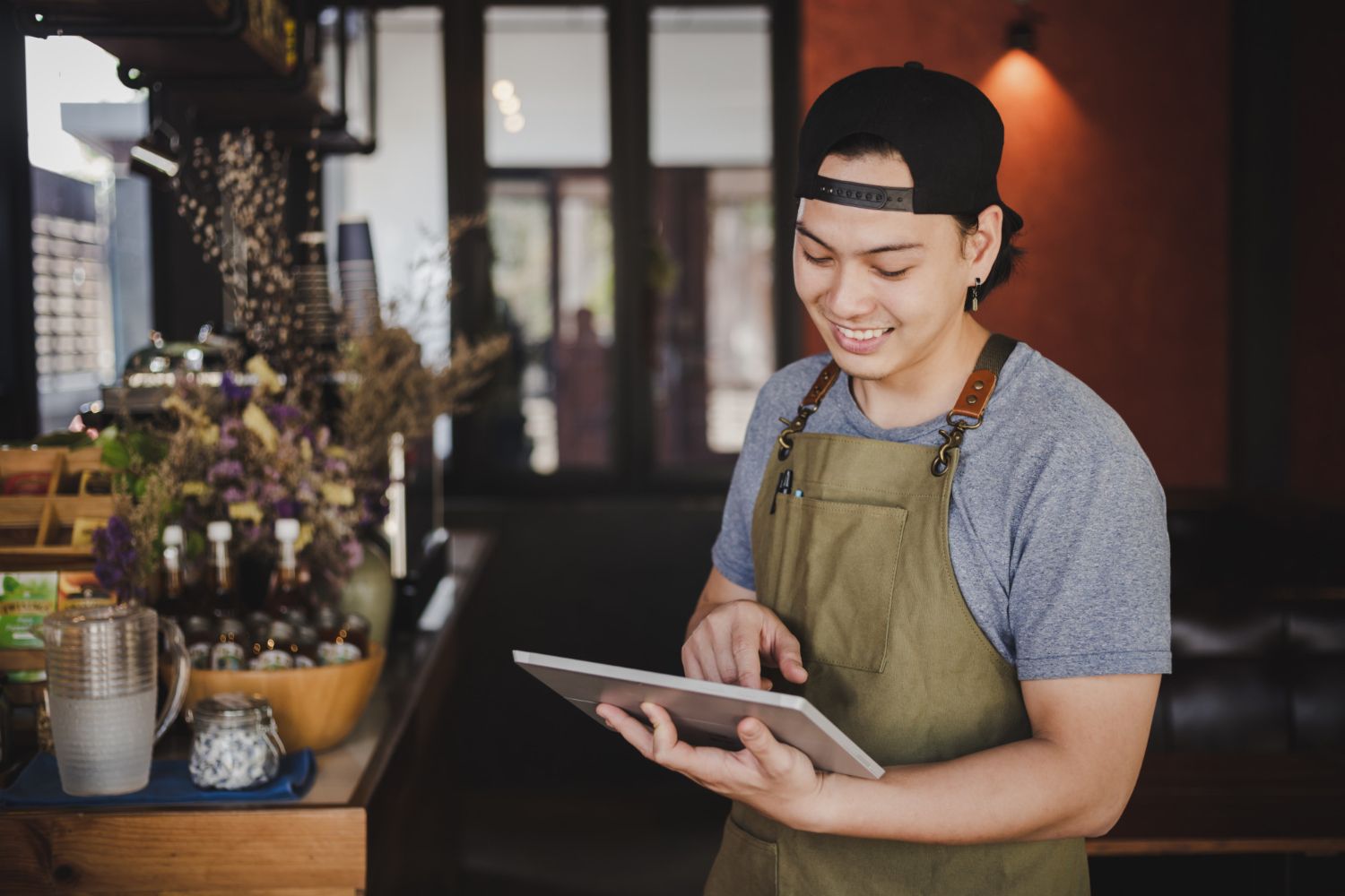 A man in an apron is using a tablet in a restaurant.