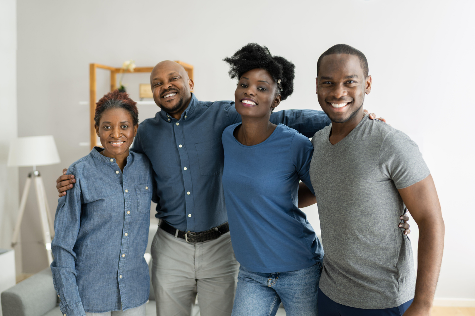 Four smiling people standing close together in a bright living room