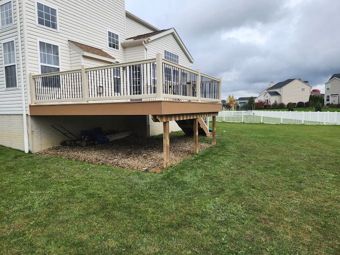 A large deck is sitting in the backyard of a house.