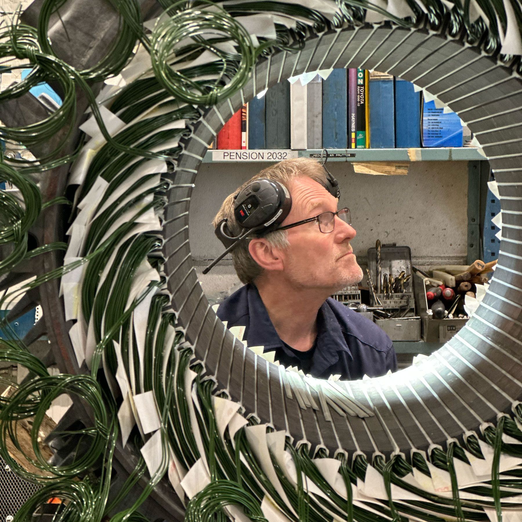 En man med hörlurar fotograferad igenom en elmotor.