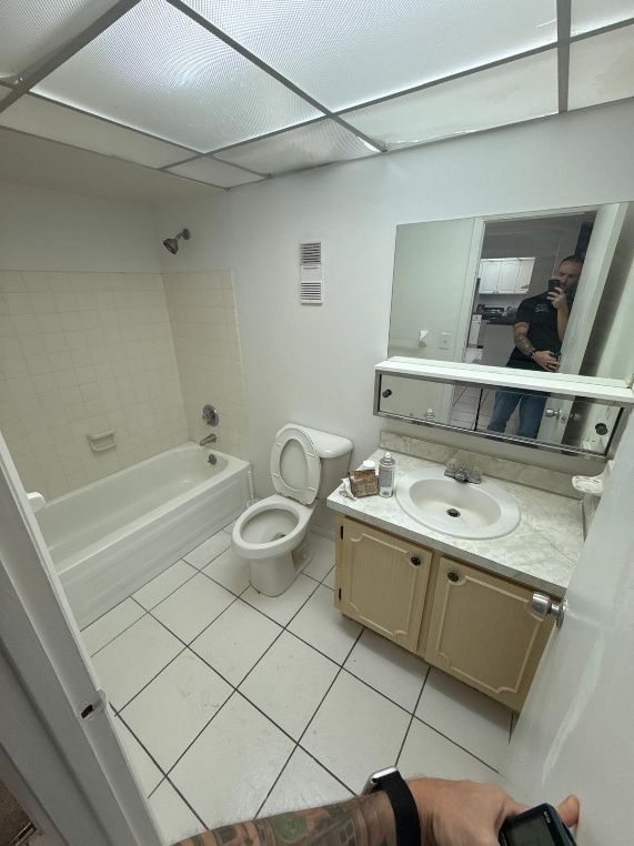Bathroom interior with a bathtub, toilet, sink, and mirror. White and beige tones throughout.