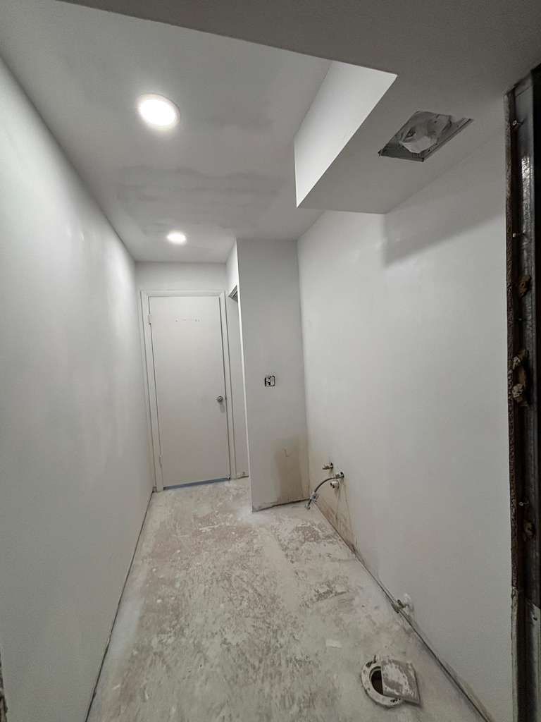 A narrow hallway with a door and recessed ceiling light