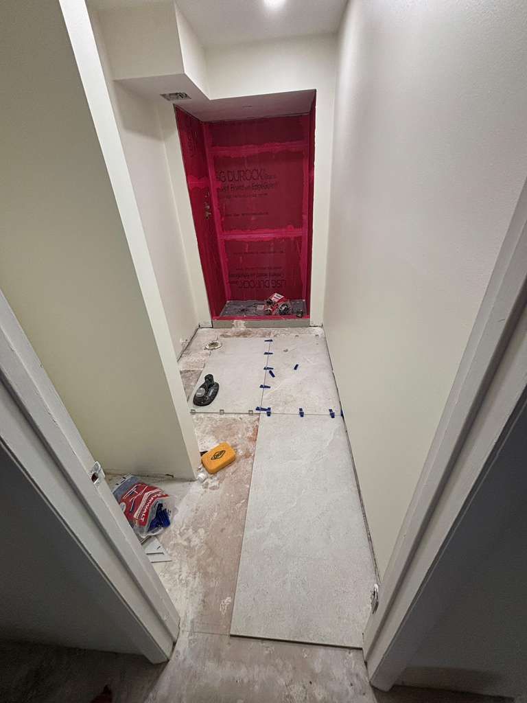 White tiled floor installation in progress, with red tile spacers.