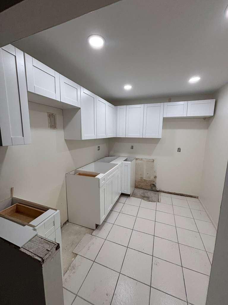 A kitchen with partially installed cabinets and tile floor