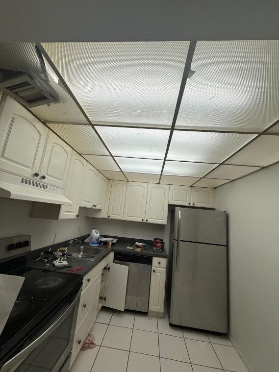 Kitchen with white cabinets, stainless steel appliances, and a fluorescent ceiling.
