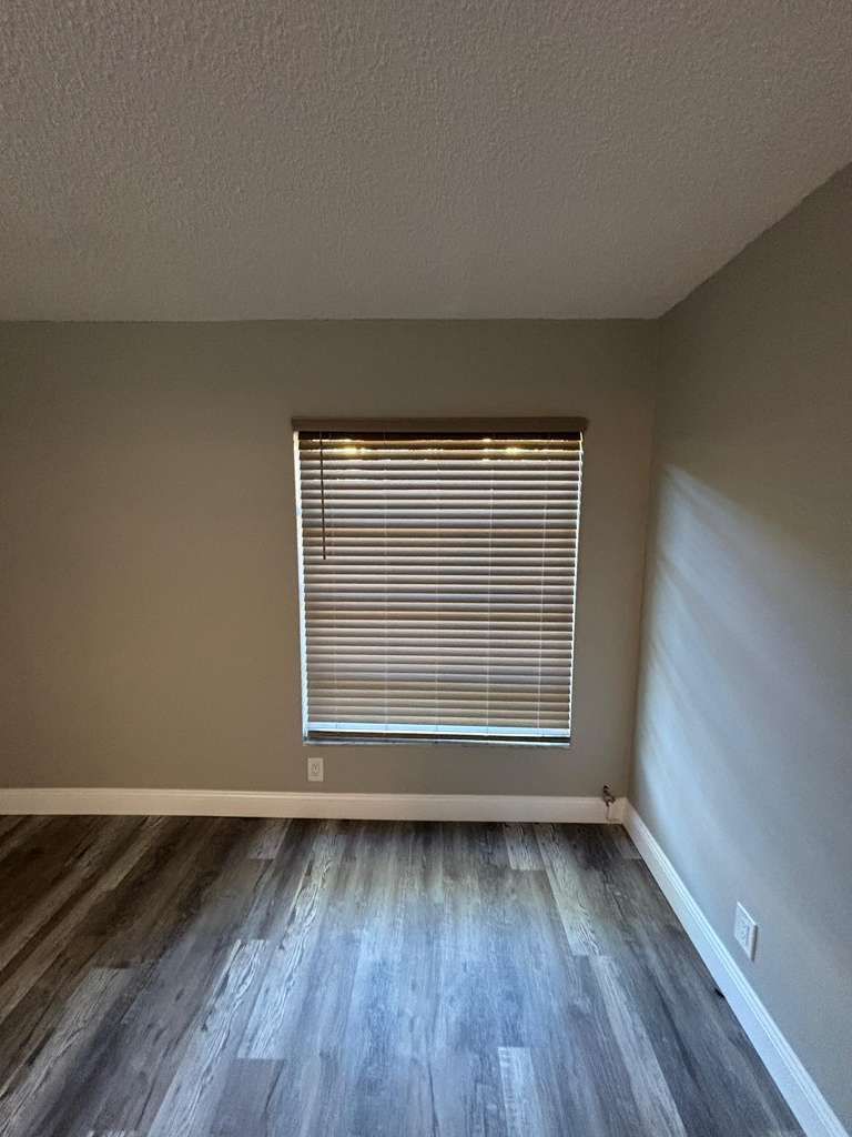 A bedroom with a window that has shades drawn