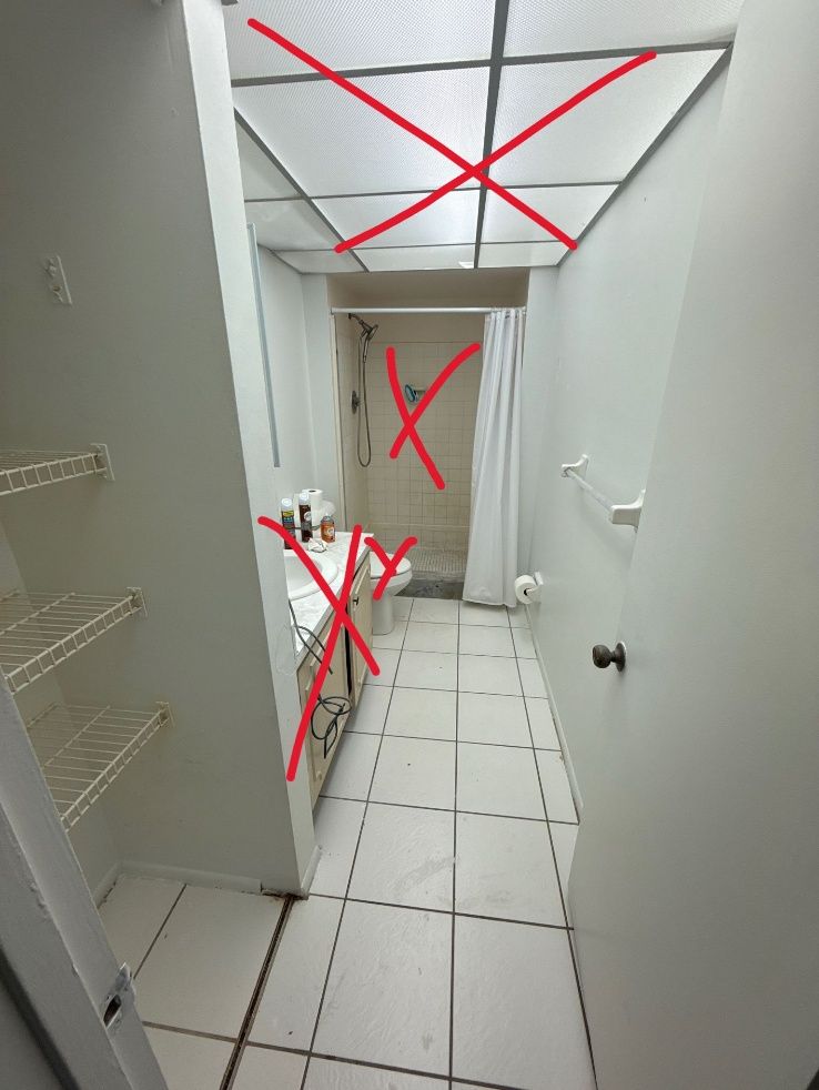 Bathroom with a white tiled floor, shower, and sink. Red