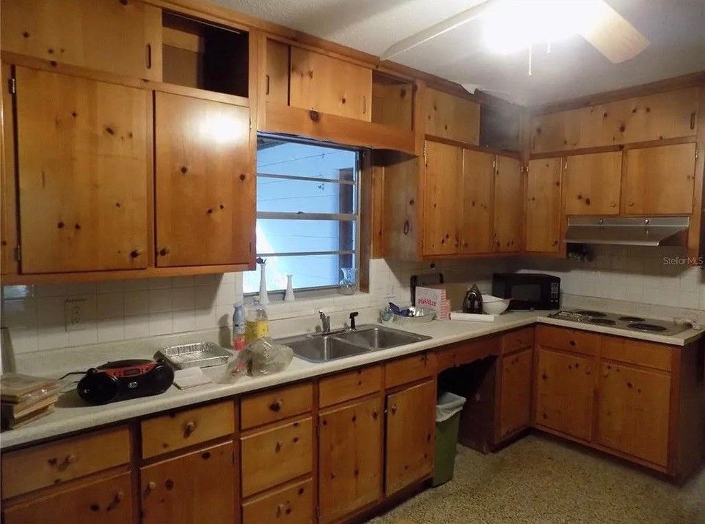 Kitchen with wood cabinets, double sink, and a microwave above the stove.