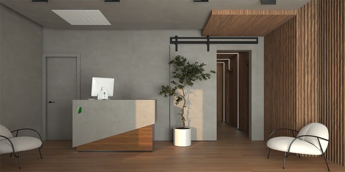 Modern office reception area with a gray and wood desk, two white chairs, a potted plant, and a hallway entrance.