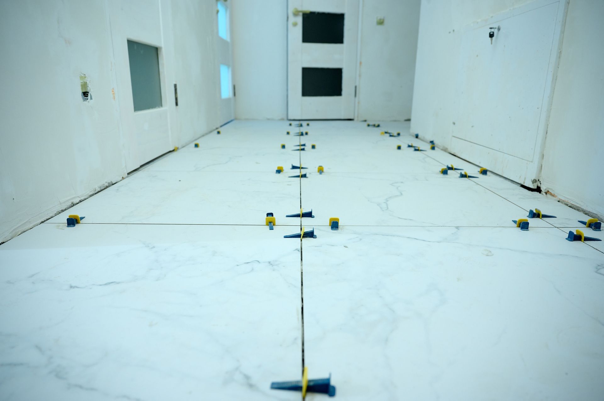 Spacious kitchen with gray island, white cabinets, granite countertops, and light wood flooring.