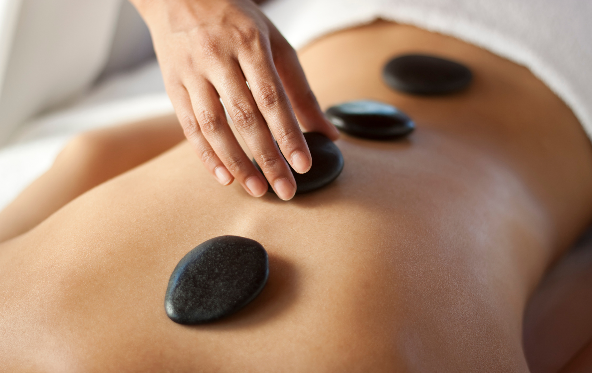 A woman is getting a massage with hot rocks on her back.