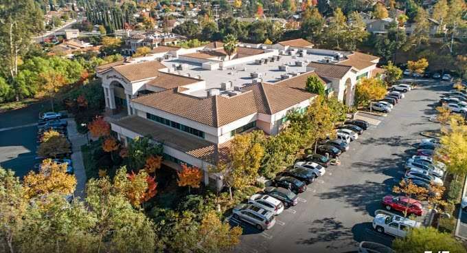 An aerial view of a large building with a lot of cars parked in front of it.