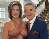 A man and a woman are posing for a picture in front of a staircase.