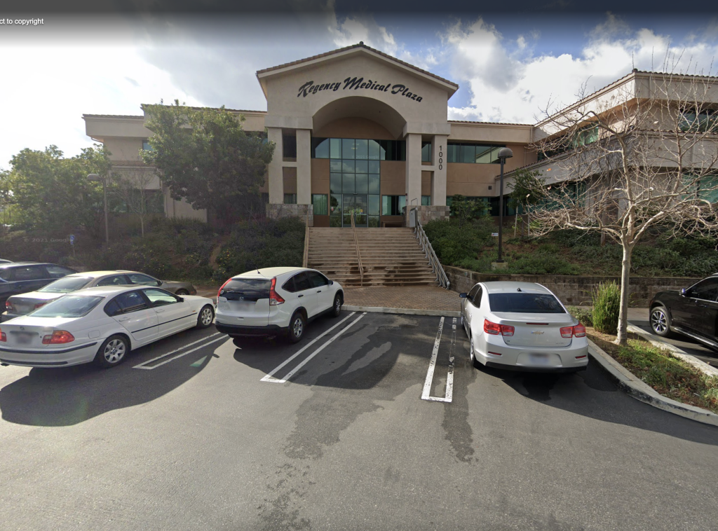 A parking lot with cars parked in front of a large building.