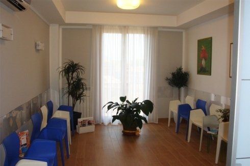 Calida sala d'attesa in toni chiari con sedie di colore blu e bianco