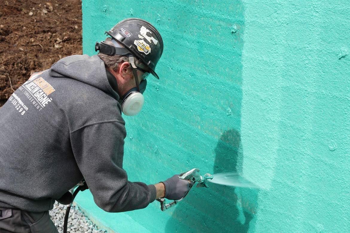 Un homme pulvérise de la peinture sur un mur végétal.