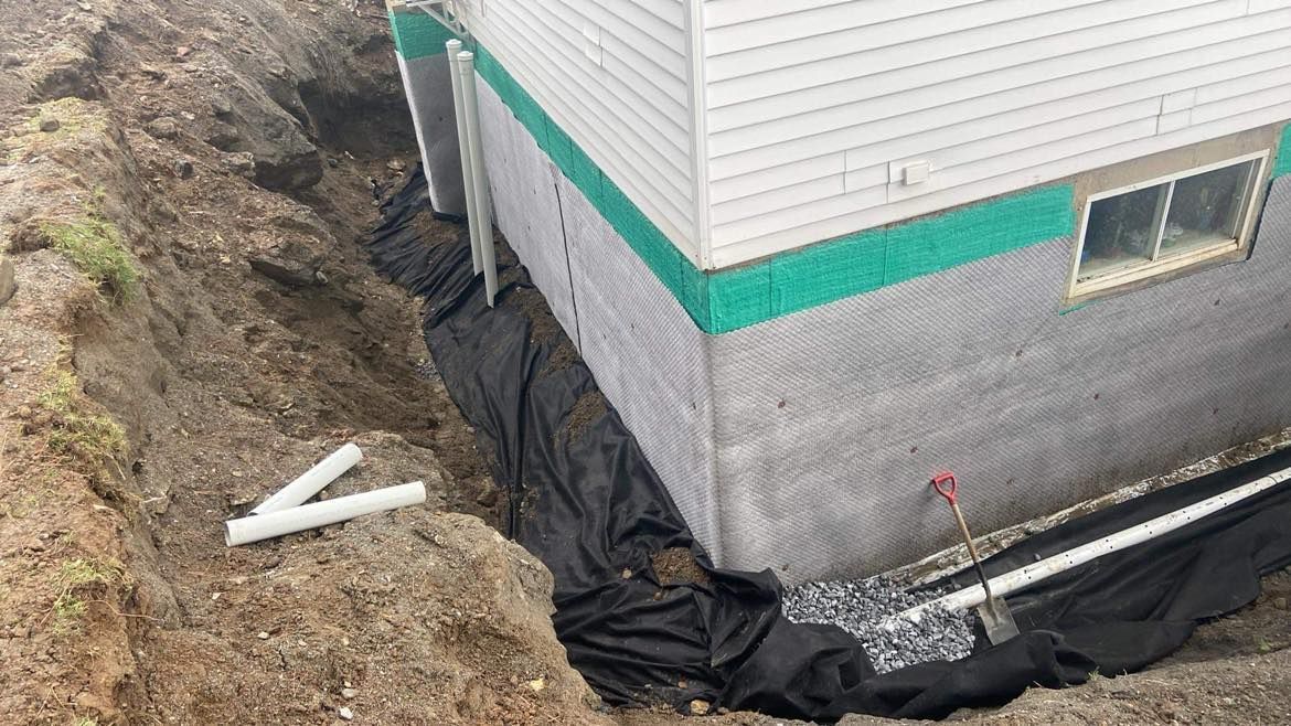 Un système de drainage est en cours d'installation sur le côté d'une maison.