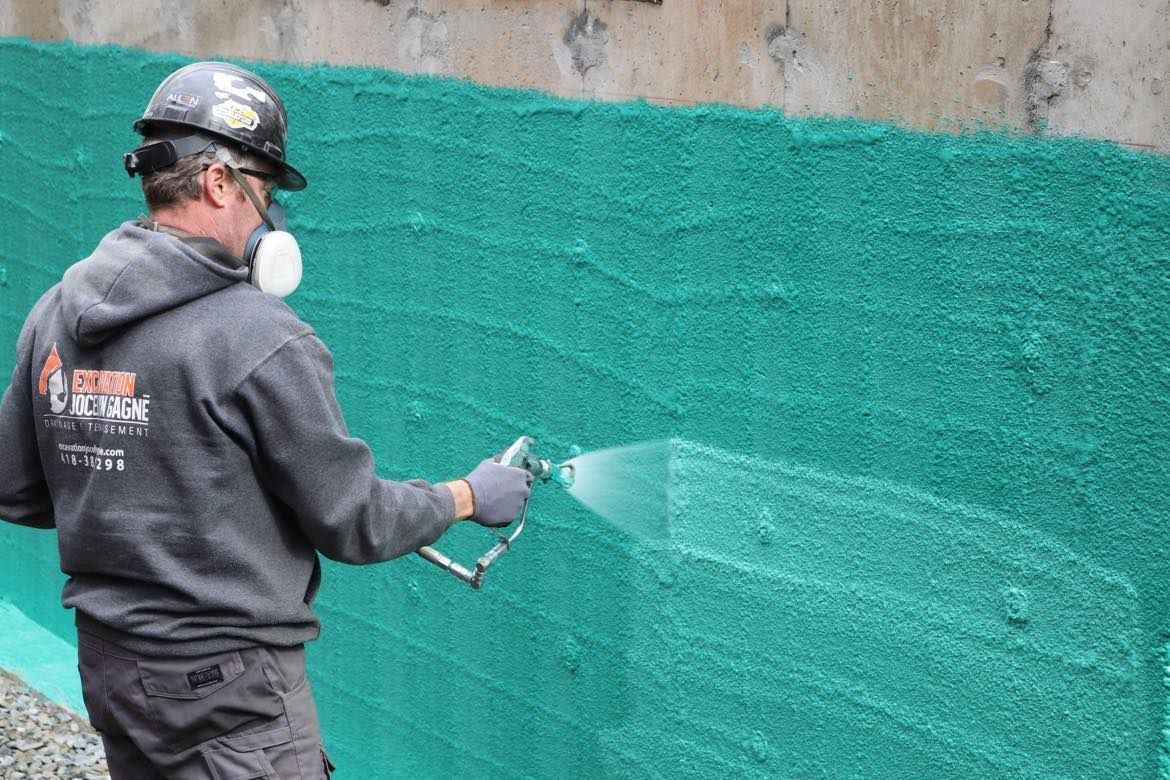 Un homme pulvérise de la peinture verte sur un mur.