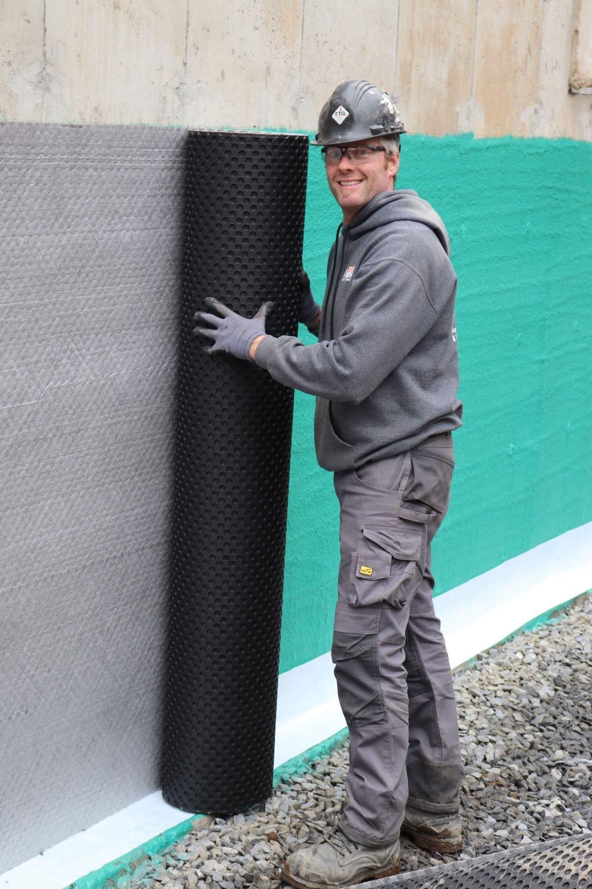 Un homme se tient debout à côté d'un mur tenant un rouleau de mousse.