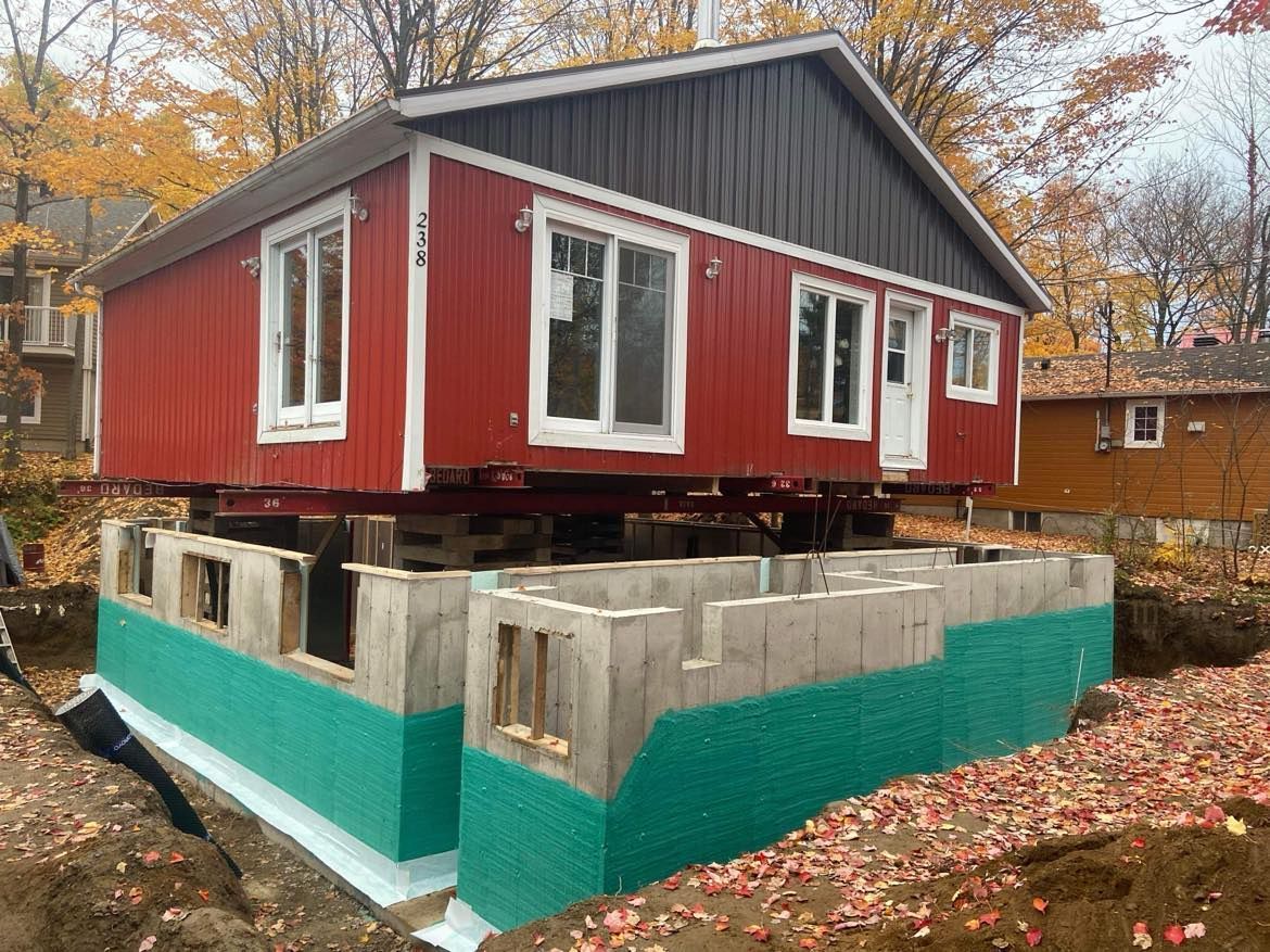 Une maison rouge est posée sur une base en béton.