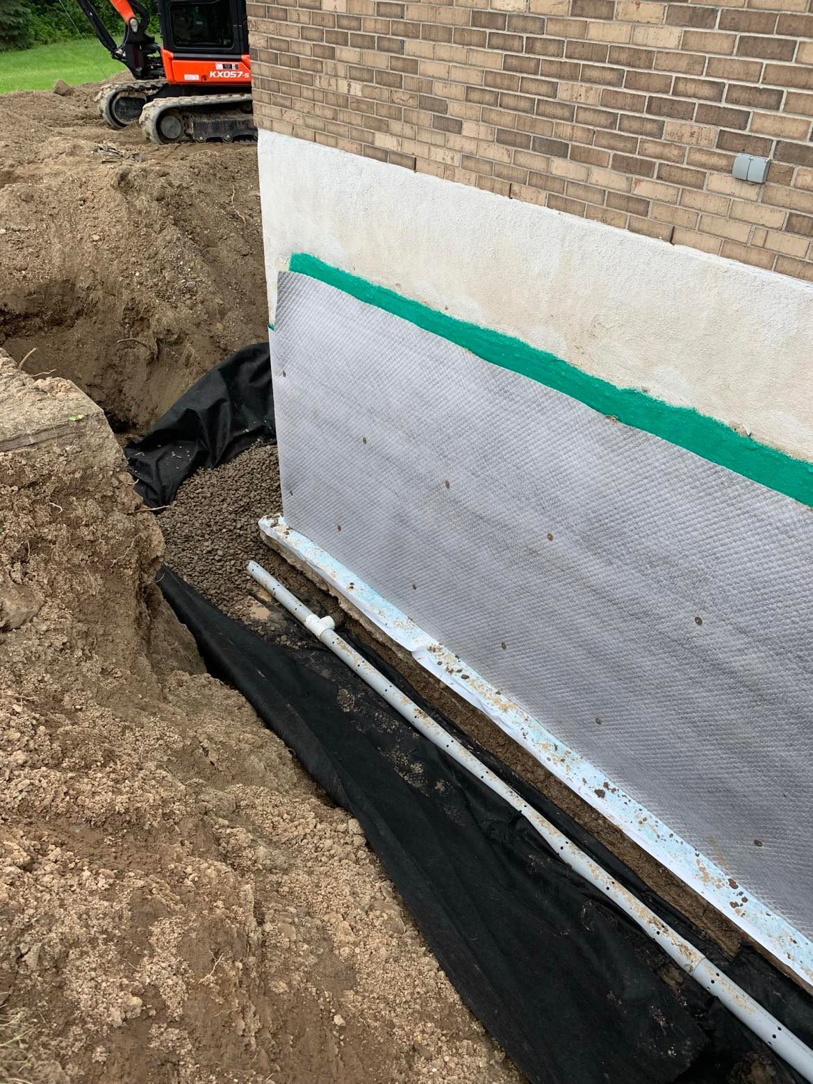 Un système de drainage est en cours d'installation sur le côté d'une maison.