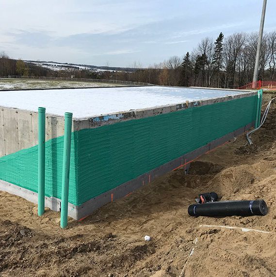 Une clôture verte entoure une structure en béton dans la terre.