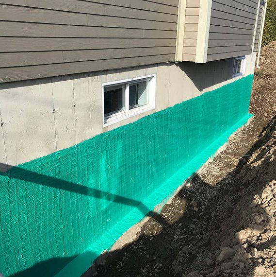 Une maison avec une barrière verte sur le côté.