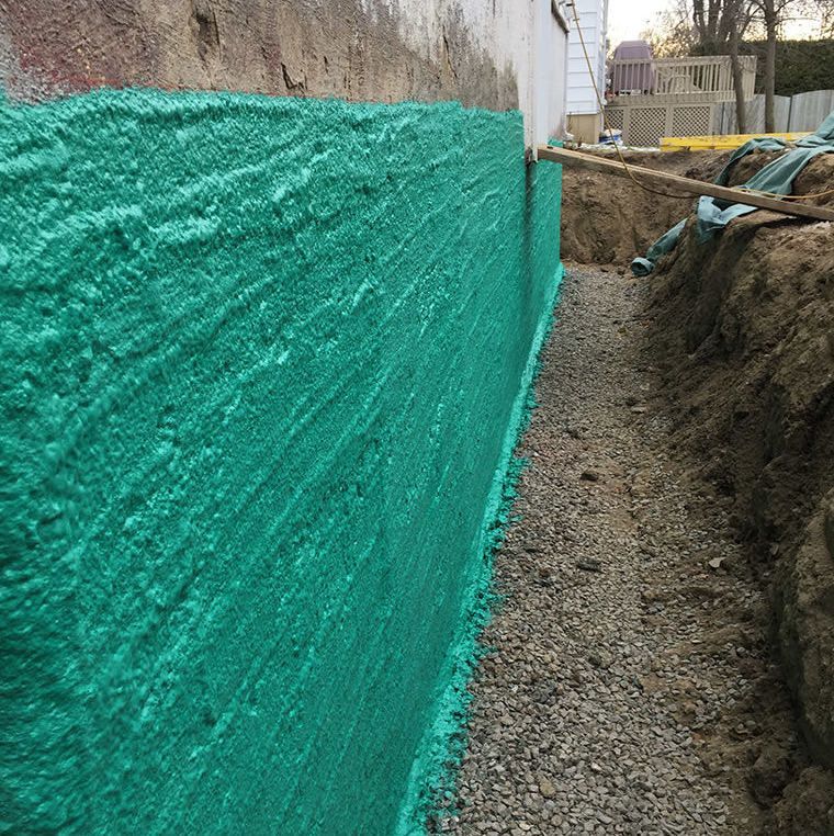 Un revêtement en mousse verte est appliqué sur un mur en béton.