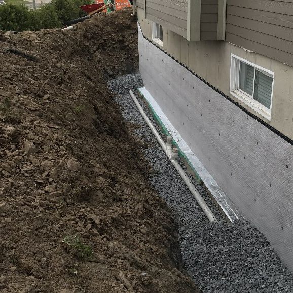 Un système de drainage est en cours d'installation sur le côté d'une maison.