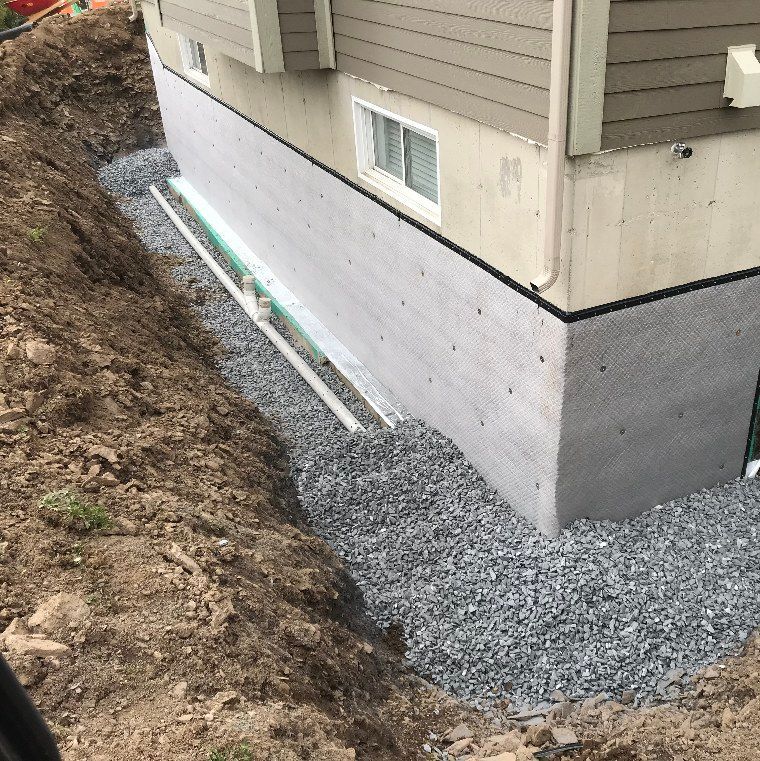 Une maison avec des fondations en béton et du gravier autour.