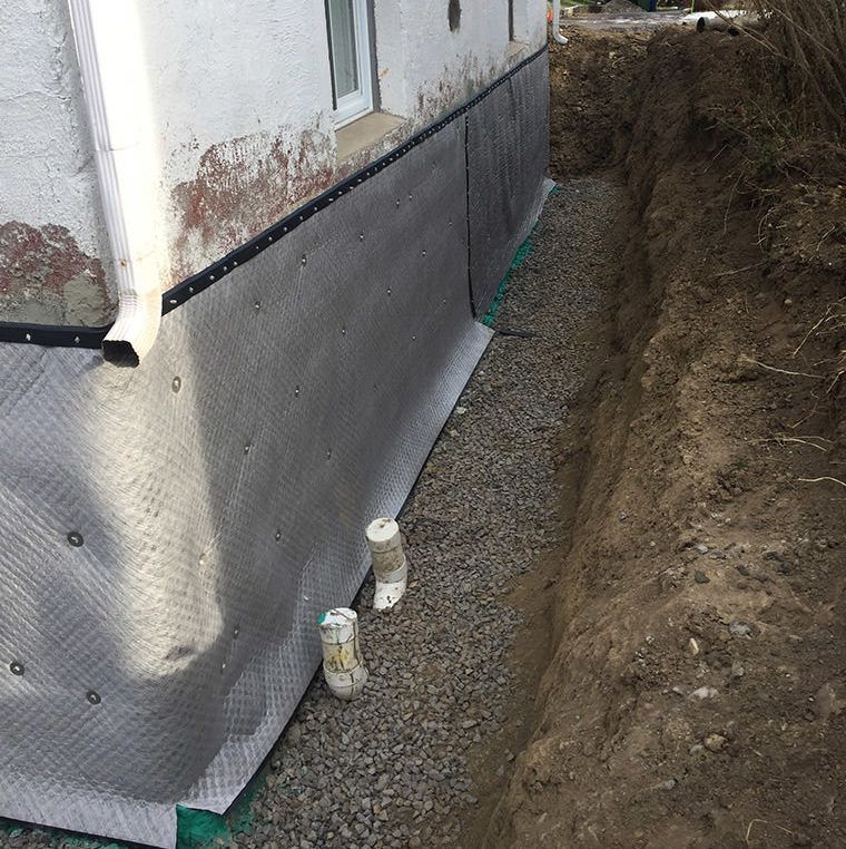 Un système de drainage est en cours d'installation sur le côté d'une maison.