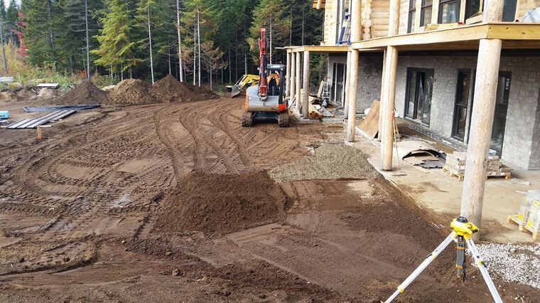 Un chantier avec beaucoup de terre et un bâtiment en arrière-plan.
