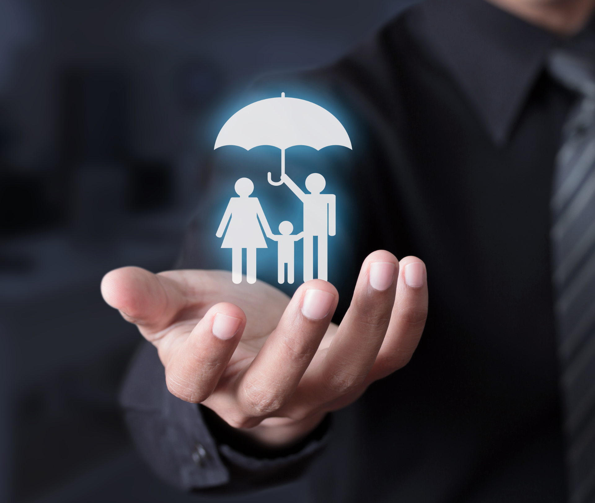 Person holding a glowing family icon under an umbrella, symbolizing insurance coverage.
