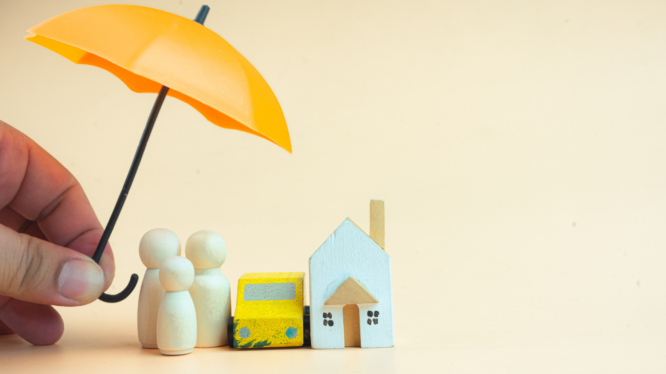 Hand holding orange umbrella over wooden family, car, and house on peach background.