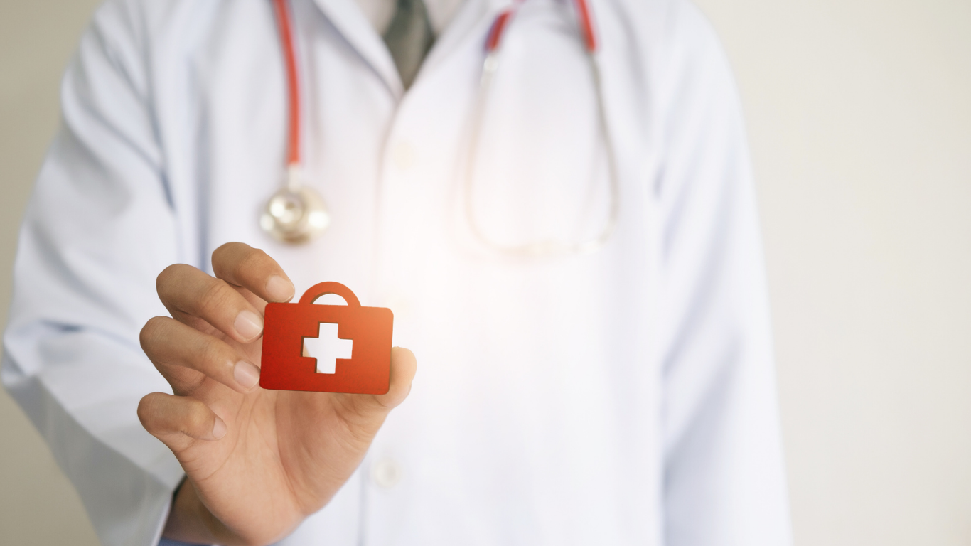 Doctor in white coat holding a red first-aid kit icon. Red stethoscope visible.