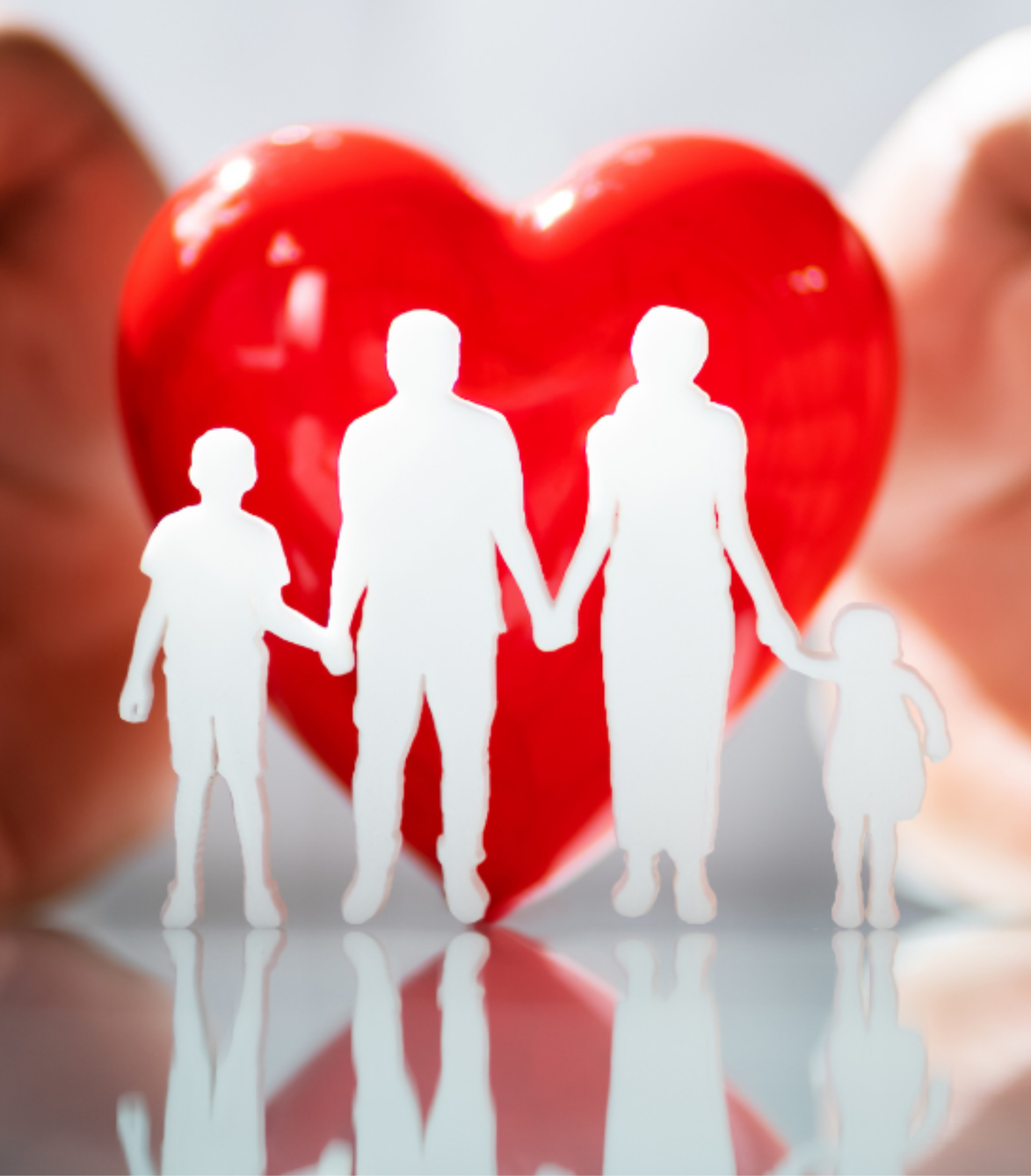 Paper cutouts of a family holding hands in front of a large red heart.