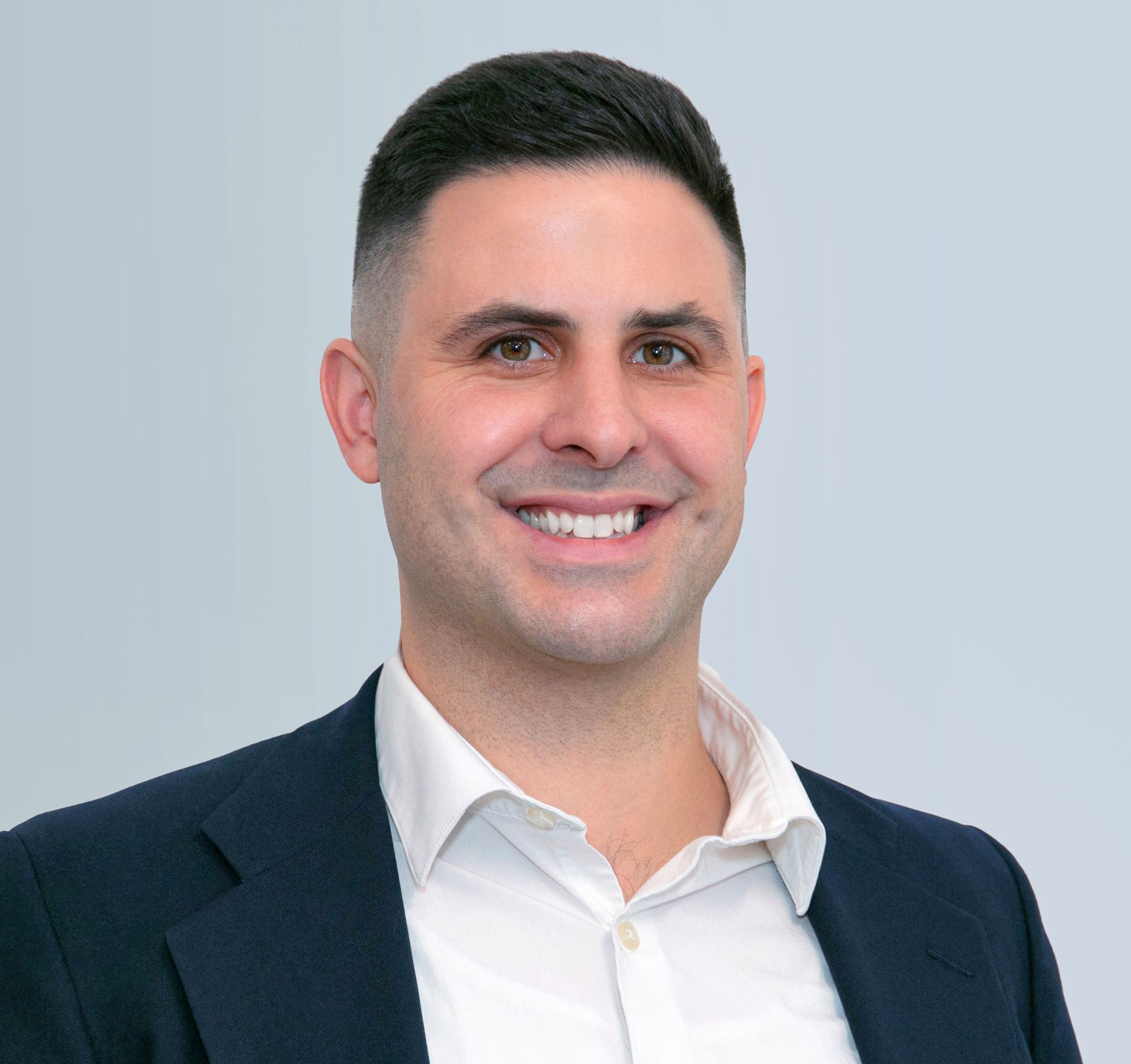 A man in a suit and white shirt is smiling for the camera.